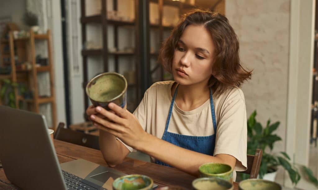 A young woman looks at a handmade ceramic mug.