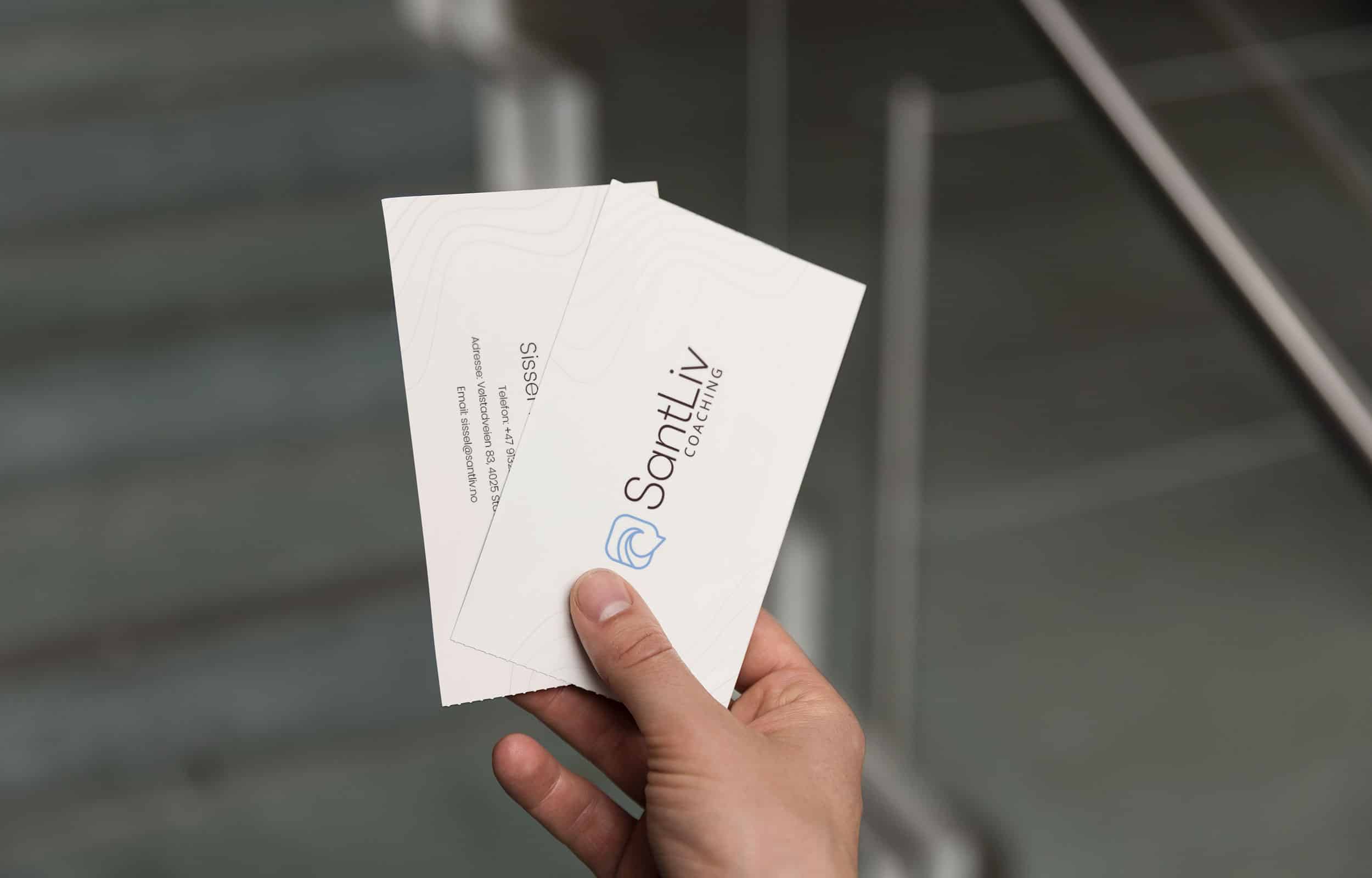 Holding two SantLiv Coaching business cards